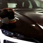 person polishing a black car